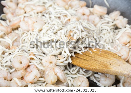 preparing the guides with shrimp in the pan and stir with wooden fork