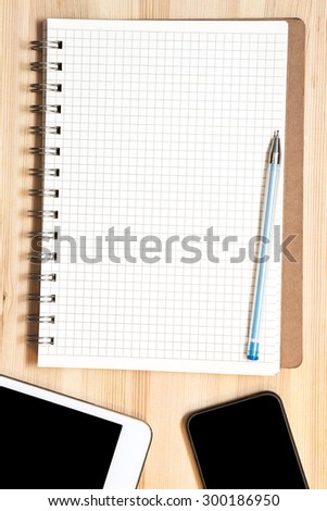 digital tablet, phone, pen and paper on wooden table