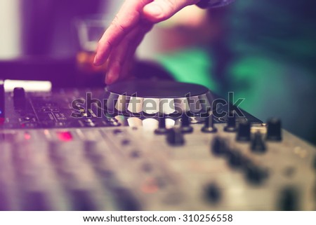Club DJ playing mixing music on vinyl turntable at party