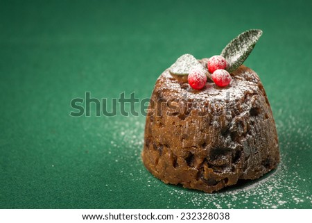 Christmas pudding with winter berries dusted with icing sugar. Shot with very shallow depth of field