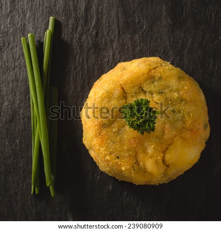 fishcake on slate background with parsley and chives