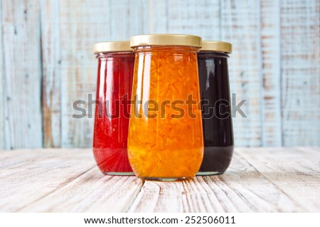 Jars of fruity jams on wooden texture