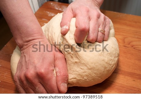 Hands kneading ball of dough with flour on cutting board