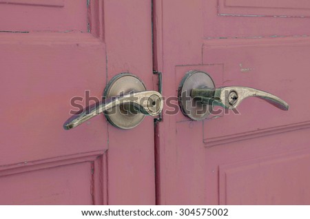 Metal doorknob with pastel purple red wood door