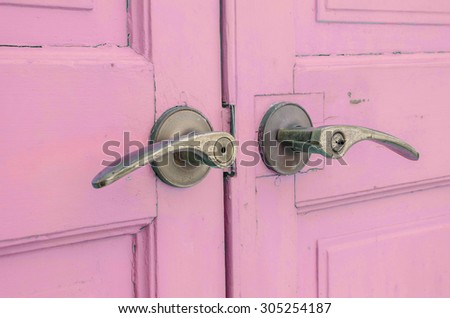 Metal doorknob with pastel pink purple wood door