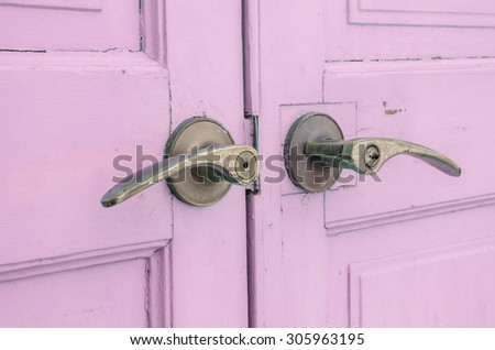 A doorknob on a pastel purple wooden door