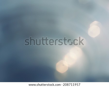 Abstract blurred blue metal texture with flares and hexagonal photographic bokeh.
