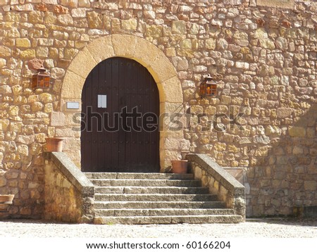 Medieval castle entrance with wooden door and steps in a bright day