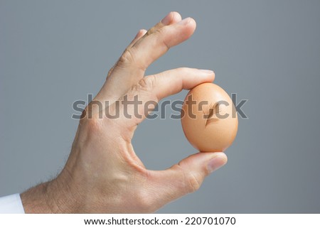 A male hand with the hen egg and feather. / Hens egg with a signature