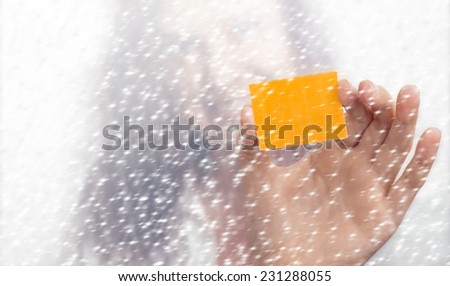 Girl\'s blurry face and hand with a yellow slip of paper in the snowfall