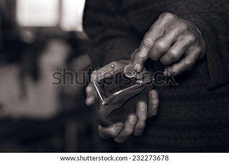 Close view of old man\'s hands putting coins to a wallet