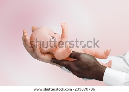 Close view of white and black man\'s hands holding a baby doll