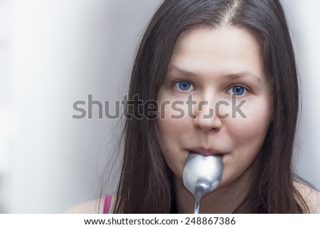Portrait of a young woman with a spoon in a mouth
