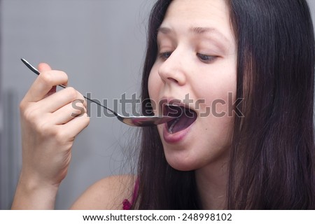 Portrait of a young woman with a spoon in a mouth
