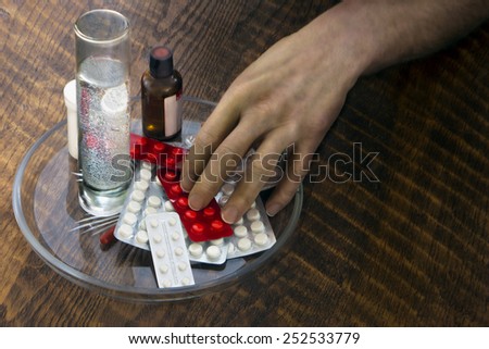 Patient\'s hand takes medicines from the plate on the table