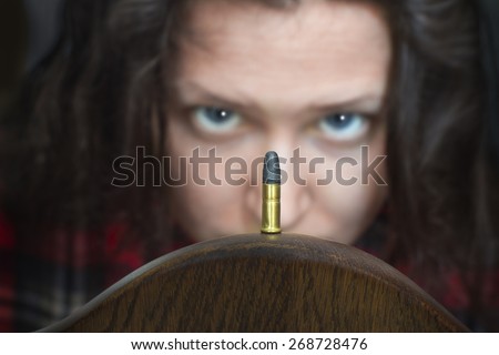 Woman looking at a guns bullet with a strange expression on her face.