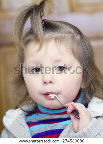 Portrait of a little girl with a spoon in the mouth