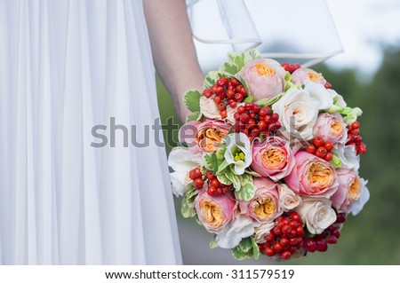 Close view of beautiful colorful wedding bouquet in a hand of a bride