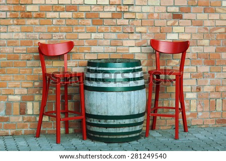 Barrel with red chairs in front ot the brick wall