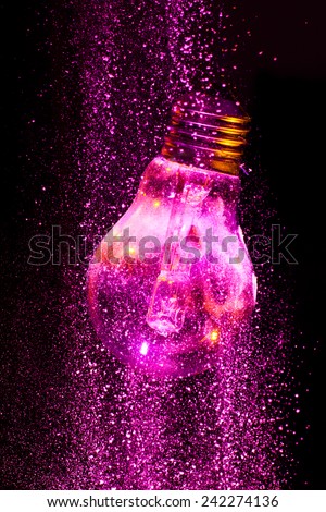 Abstract Purple colorful light bulb with powder on black background