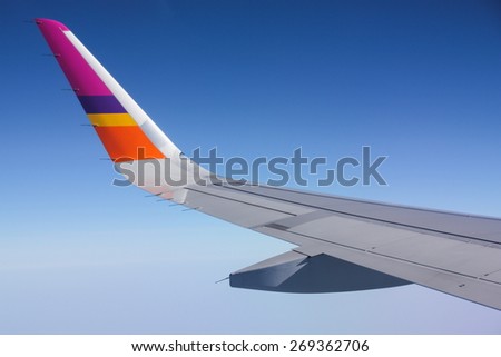 BANGKOK - APRIL 4, 2015 : Wing of an Thai Smile Airplane flying above the clouds view from window on April 4, 2015, Bangkok, Thailand.
