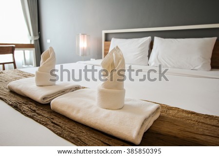 Two towels on the bed in hotel room.
