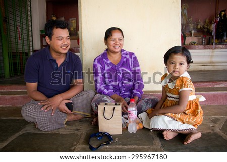 Parents and a little kid sitting on the floor at the temple in Bagan, Myanmar, February 14, 2013