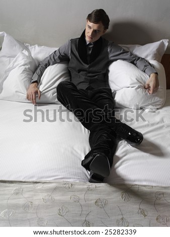 young man in suit sitting on the bed in suit