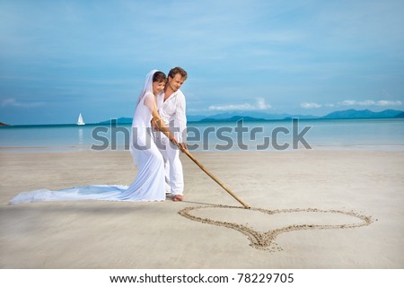 stock photo beautiful couple on the beach in wedding dress drawing heart