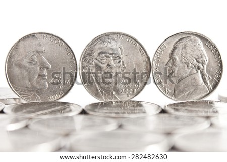 Thomas Jefferson faces on three five cents coins standing on the edge white background and coins on the foreground