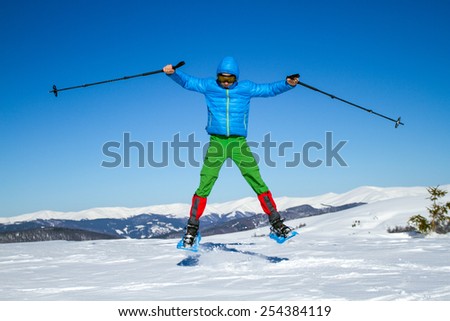 Young man having fun while snowshoeing outdoors on a lovely snowy winter day.