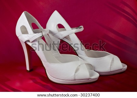 White high-heeled shoes over red background