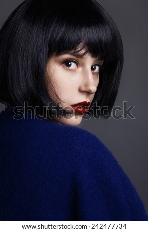 Beautiful woman in a black wig and a blue coat. Perfect makeup. Closeup.
