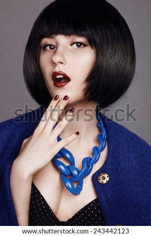 Beautiful woman in a black wig and a blue coat. Perfect makeup.