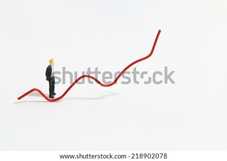Miniature people standing beside the red trend line