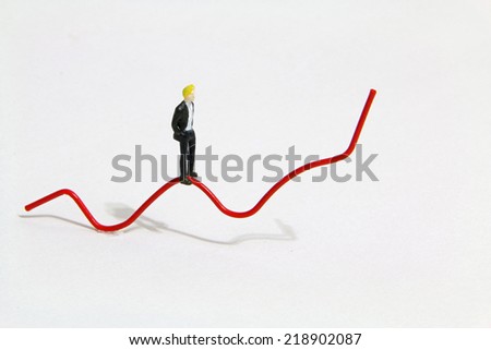 Miniature people walking on the red trend line