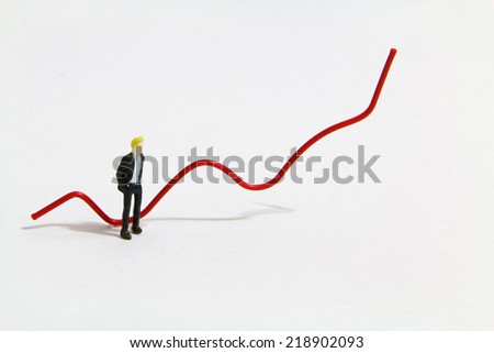 Miniature people standing beside the red trend line