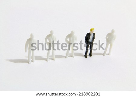 The outstanding miniature business people standing with other  miniature people on the white background