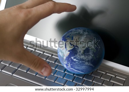 grabbing the world with my hand in front of a laptop