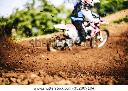 Biker accelerating during a motocross race with flying mud and debris