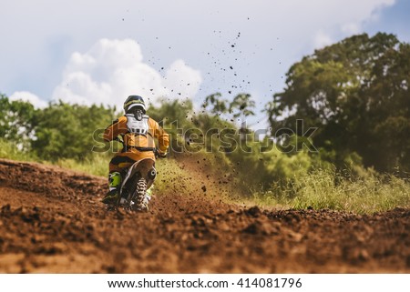 Motocross racer accelerating in dirt track with flying mud debris