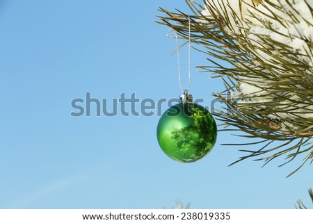 The green sphere hanging on a Christmas tree against the blue sky