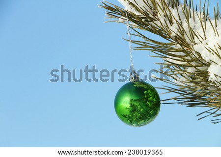 The green sphere hanging on a Christmas tree against the blue sky