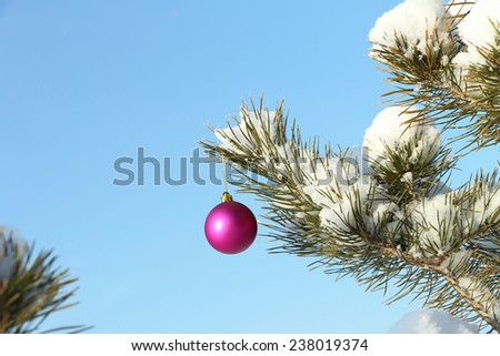 The lilac sphere hanging on a Christmas tree against the blue sky