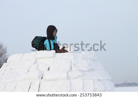 The man with a backpack on a snow field building of pieces of snow an igloo in the winter