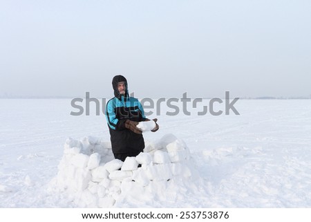 The man on a snow field building of pieces of snow an igloo in the winter