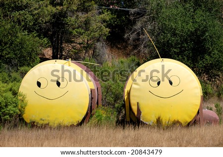 Two tanks with yellow smiley faces painted on them standing next to each other in the field