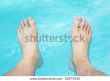 Two feet relaxing in the swimming pool water.
