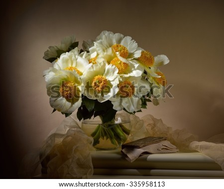 bouquet from yellow peonies with old book on table on beige background