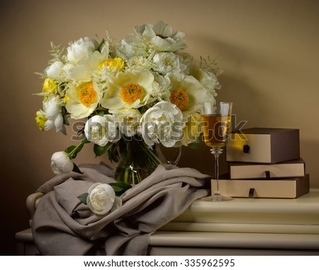 bouquet from peonies with glass of white wine and old boxes on table on beige background